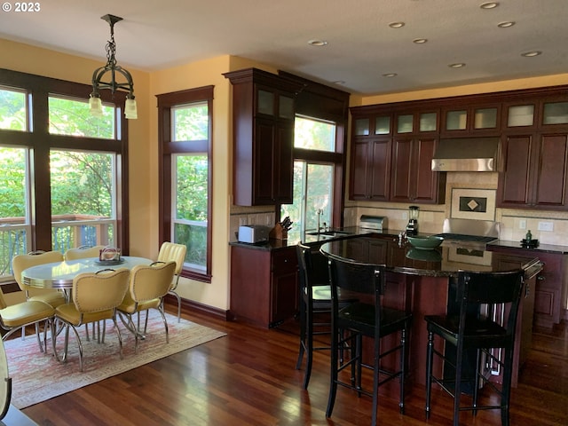 kitchen featuring tasteful backsplash, a kitchen island, dark hardwood / wood-style flooring, decorative light fixtures, and ventilation hood