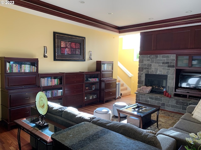 living room featuring crown molding, a fireplace, and wood-type flooring