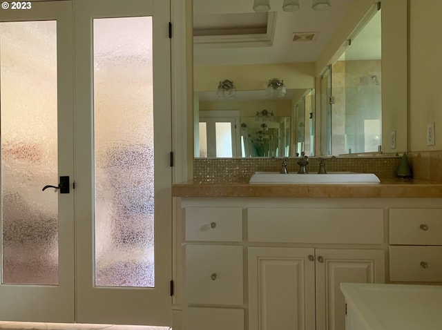 bathroom featuring vanity, french doors, and backsplash