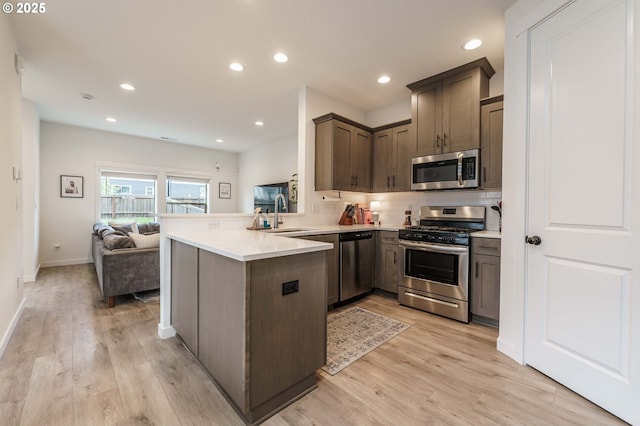 11492 SE Mt Talbert Ave, Happy Valley, OR 97086 - kitchen featuring appliances with stainless steel finishes, a peninsula, open floor plan, a sink, and light wood-type flooring