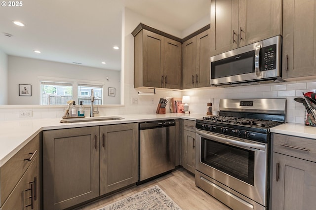 11492 SE Mt Talbert Ave, Happy Valley, OR 97086 - kitchen with appliances with stainless steel finishes, a sink, light wood-type flooring, backsplash, and light countertops