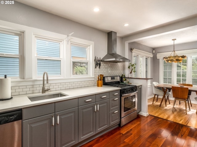1405 NE 47th Ave, Portland, OR 97213 - kitchen featuring appliances with stainless steel finishes, wall chimney exhaust hood, gray cabinets, a chandelier, and dark wood-style floors