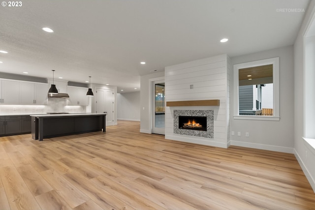 unfurnished living room with a tiled fireplace and light hardwood / wood-style flooring