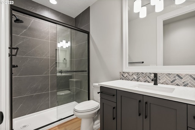 bathroom with walk in shower, backsplash, toilet, and vanity