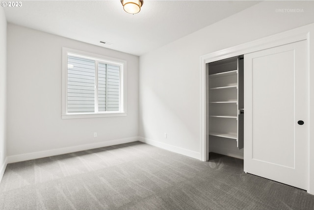 unfurnished bedroom with dark carpet and a closet