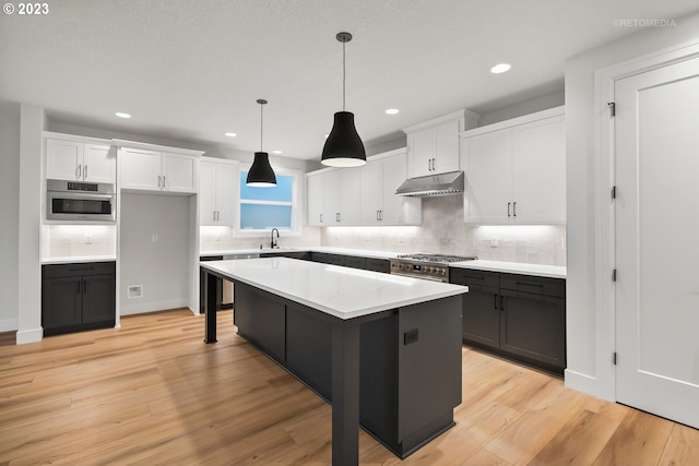 kitchen with decorative light fixtures, light hardwood / wood-style floors, a center island, and white cabinetry