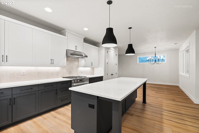 kitchen with tasteful backsplash, light hardwood / wood-style floors, white cabinetry, a notable chandelier, and pendant lighting