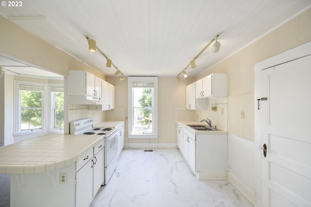 kitchen with rail lighting, white cabinets, electric stove, and a wealth of natural light