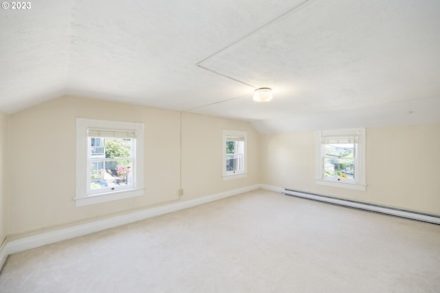 interior space with a textured ceiling, a baseboard radiator, and lofted ceiling