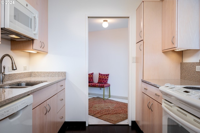 kitchen featuring white appliances, light stone countertops, sink, and light brown cabinets