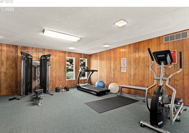 workout room with wooden walls and a textured ceiling