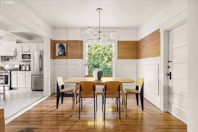 dining room featuring ornamental molding, wainscoting, and wood finished floors
