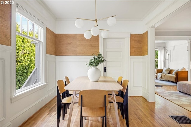 dining space with a decorative wall, plenty of natural light, and wainscoting