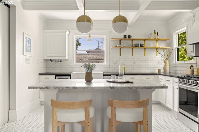 kitchen featuring light floors, a kitchen breakfast bar, white cabinetry, tasteful backsplash, and gas stove