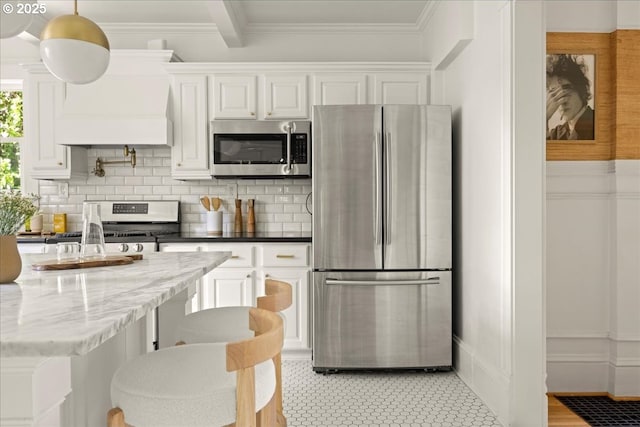kitchen featuring backsplash, crown molding, light stone countertops, stainless steel appliances, and white cabinetry