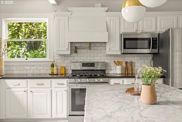 kitchen featuring dark stone counters, tasteful backsplash, stainless steel appliances, and white cabinetry