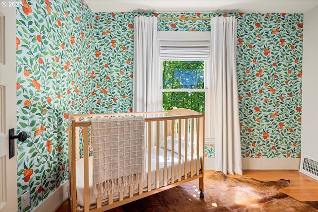 interior space with baseboards, wallpapered walls, and wood finished floors