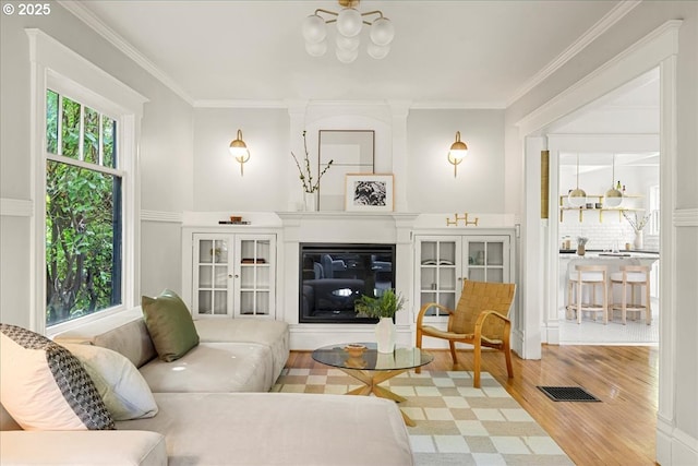 living room featuring an inviting chandelier, ornamental molding, and wood finished floors