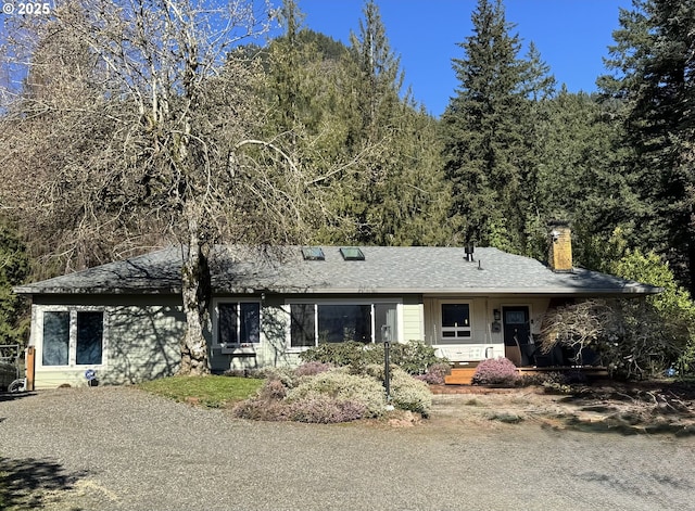 ranch-style home with a chimney and a shingled roof