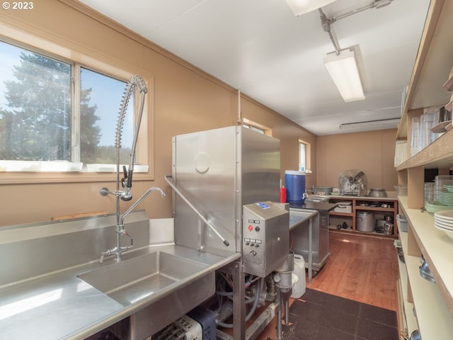 kitchen with dark hardwood / wood-style flooring, ornamental molding, sink, and stainless steel counters