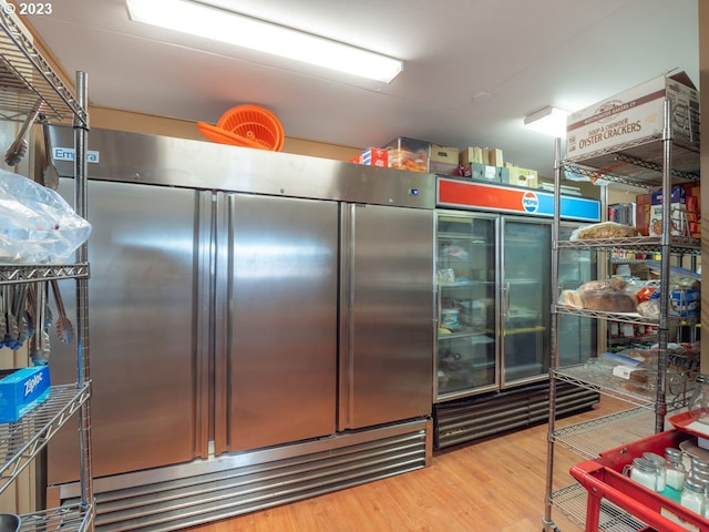 interior space featuring stainless steel built in fridge and light hardwood / wood-style flooring