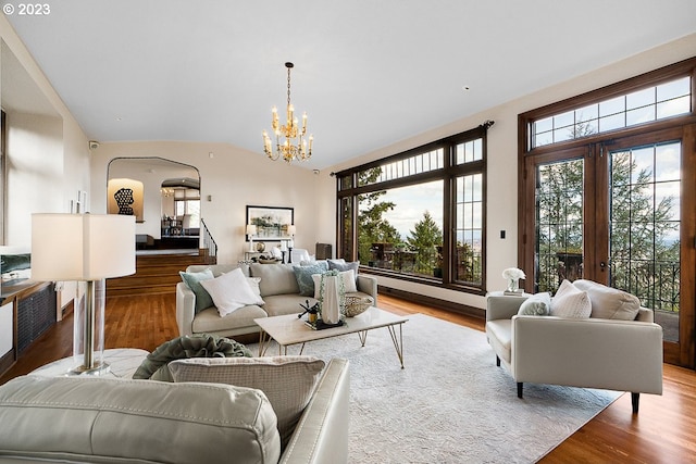 living room featuring an inviting chandelier, light hardwood / wood-style floors, vaulted ceiling, and a wealth of natural light