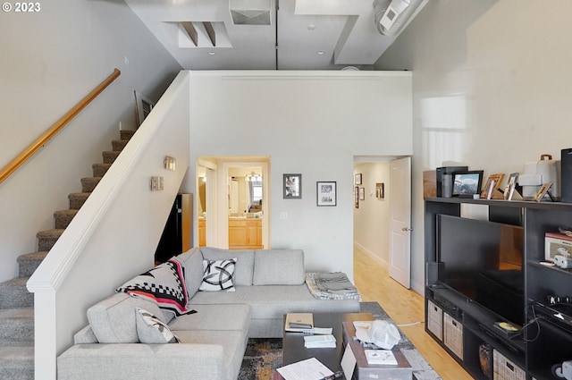 living room with light hardwood / wood-style floors and a towering ceiling