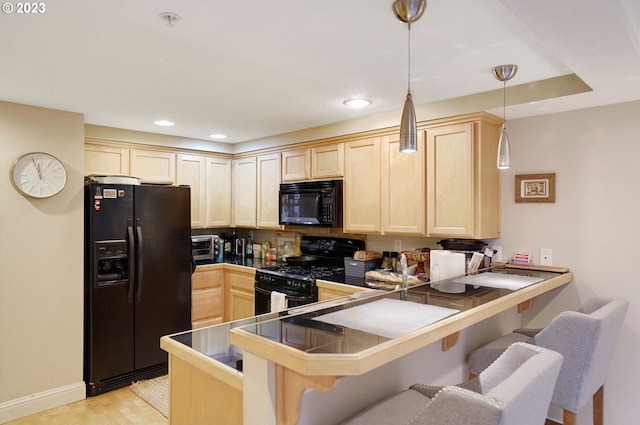 kitchen featuring a kitchen breakfast bar, hanging light fixtures, kitchen peninsula, and black appliances