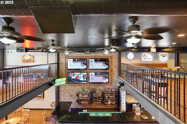 interior space with ceiling fan, brick wall, and hardwood / wood-style floors