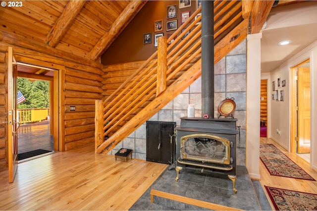 living room with a wood stove, rustic walls, dark hardwood / wood-style flooring, vaulted ceiling with beams, and wooden ceiling