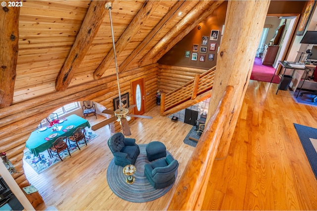 living room featuring wood ceiling, vaulted ceiling with beams, log walls, and light wood-type flooring