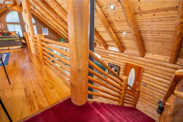 staircase featuring rustic walls, wooden ceiling, vaulted ceiling with beams, and light wood-type flooring