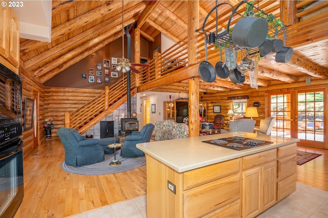 kitchen featuring ceiling fan, a wood stove, rustic walls, and light brown cabinets