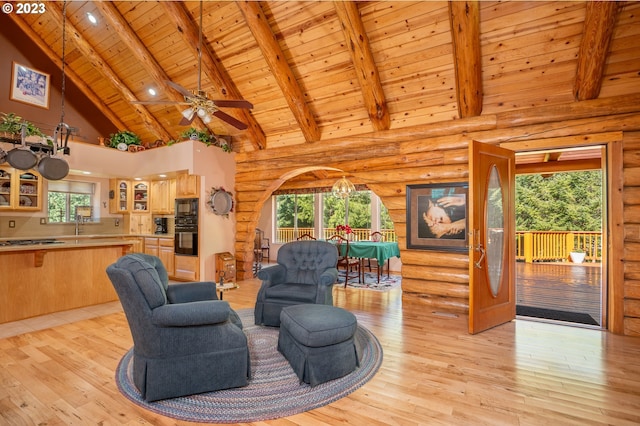 living room with light hardwood / wood-style flooring, beamed ceiling, rustic walls, wooden ceiling, and high vaulted ceiling