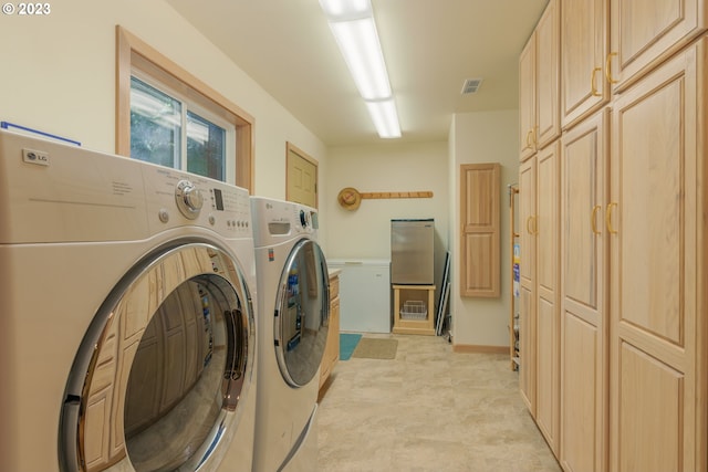 clothes washing area with washing machine and clothes dryer, cabinets, and light tile flooring