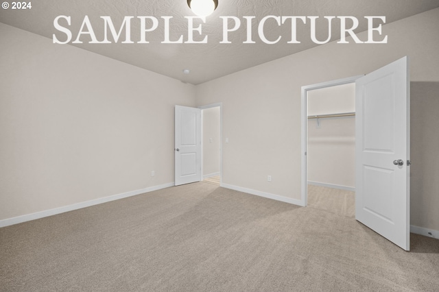 unfurnished bedroom with carpet flooring, a walk in closet, and a closet