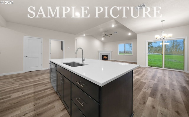 kitchen featuring light wood-type flooring, stainless steel dishwasher, sink, lofted ceiling, and an island with sink