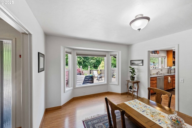 dining area with baseboards and light wood finished floors