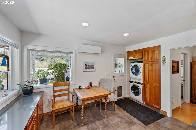 clothes washing area featuring an AC wall unit, laundry area, plenty of natural light, and stacked washer / dryer