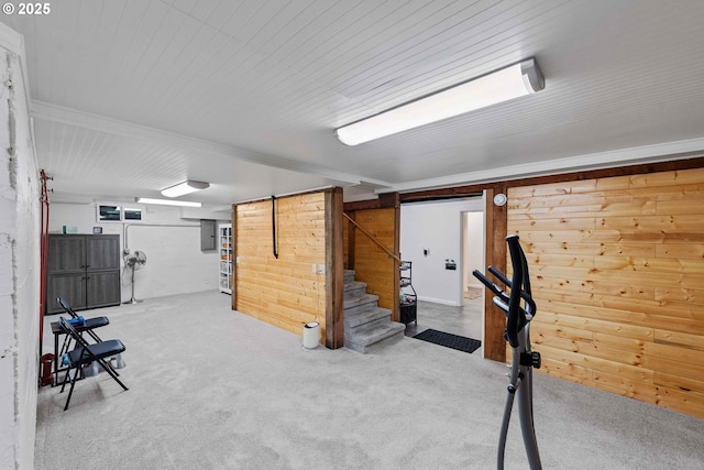 finished basement with carpet flooring, stairs, and wooden walls