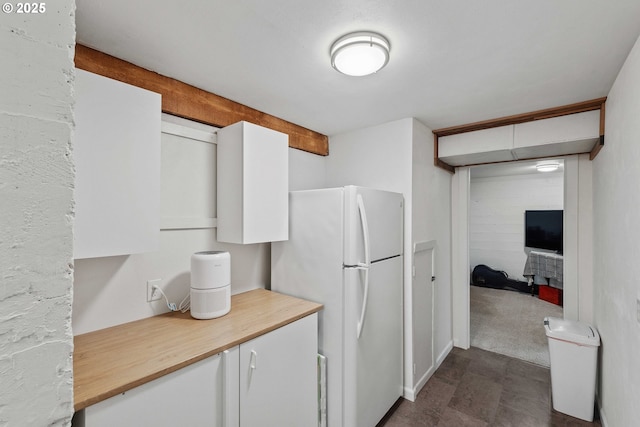 kitchen with freestanding refrigerator, wood counters, and white cabinets