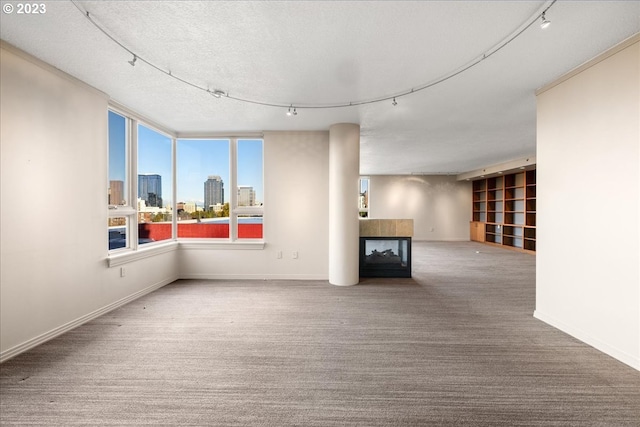 unfurnished living room featuring carpet, rail lighting, and a textured ceiling