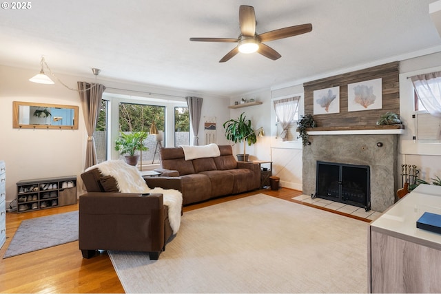 living room with plenty of natural light, a tiled fireplace, and light hardwood / wood-style flooring