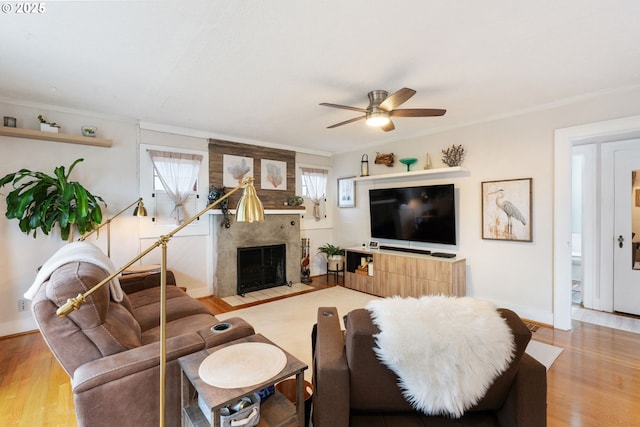 living room with a premium fireplace, ornamental molding, ceiling fan, and light hardwood / wood-style floors