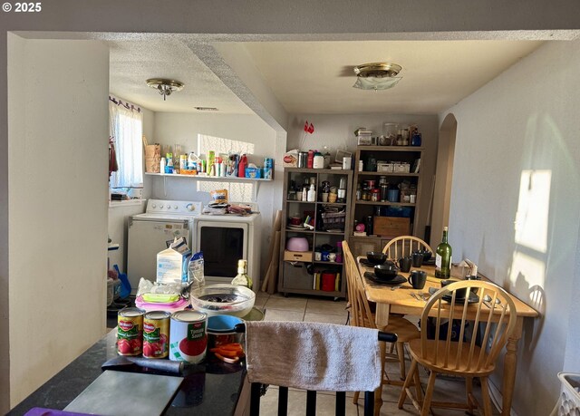 tiled dining space featuring a textured ceiling and independent washer and dryer