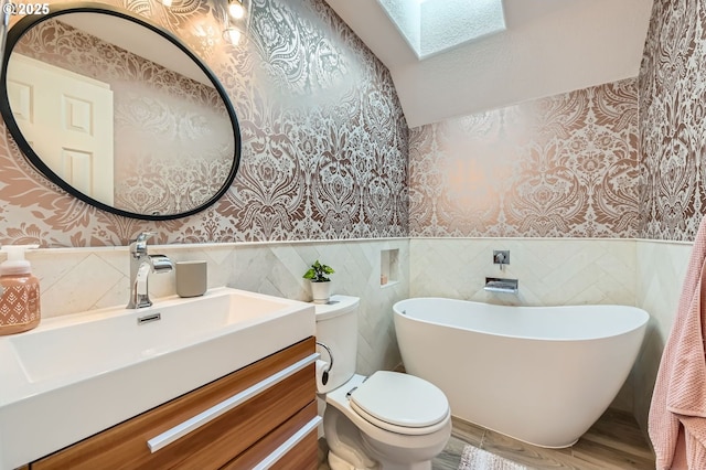 17472 NW Gilbert Ln, Portland, OR 97229 - bathroom featuring wallpapered walls, a skylight, a freestanding tub, a wainscoted wall, and vanity