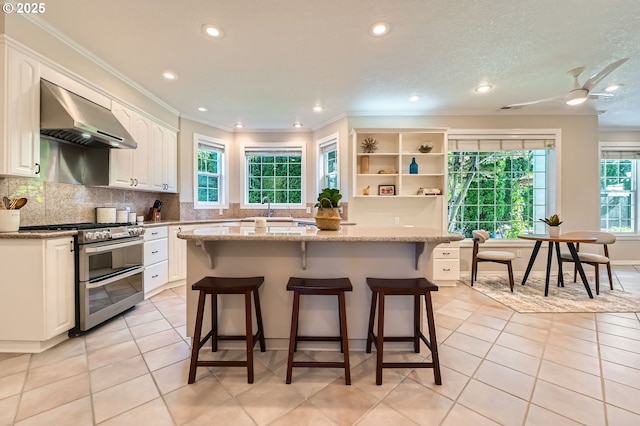 17472 NW Gilbert Ln, Portland, OR 97229 - kitchen with double oven range, ventilation hood, crown molding, healthy amount of natural light, and recessed lighting