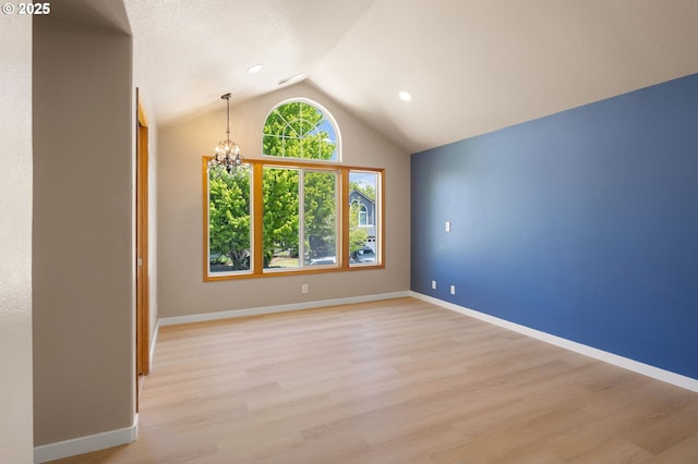 unfurnished room featuring lofted ceiling, a chandelier, light wood-style floors, and baseboards