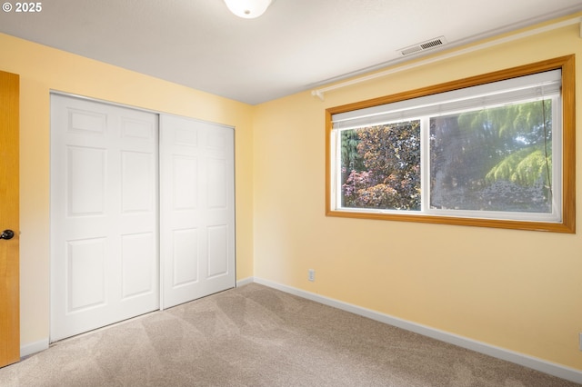 unfurnished bedroom featuring carpet, multiple windows, baseboards, and a closet