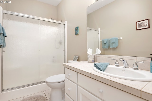 bathroom featuring tile floors, a shower with shower door, large vanity, and toilet